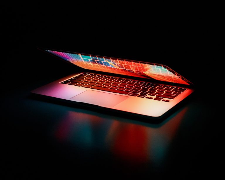 Eingeschalter halb geöffneter Laptop im Dunkeln