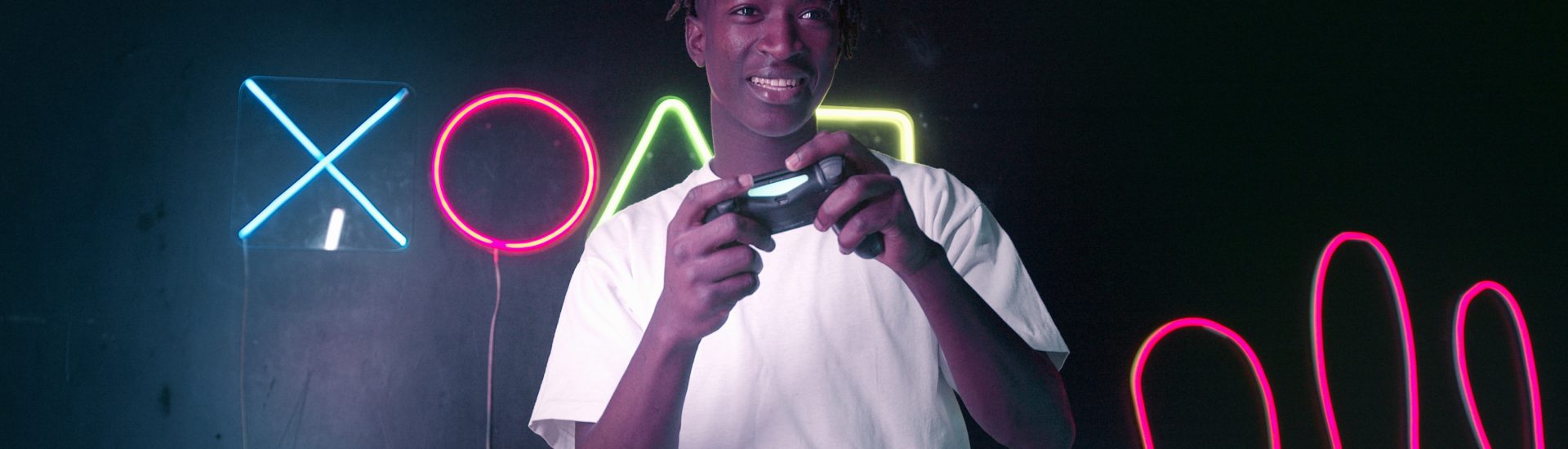 Jugendlicher hält Spielkonsole in der Hand mit LED Lichter im Hintergrund
