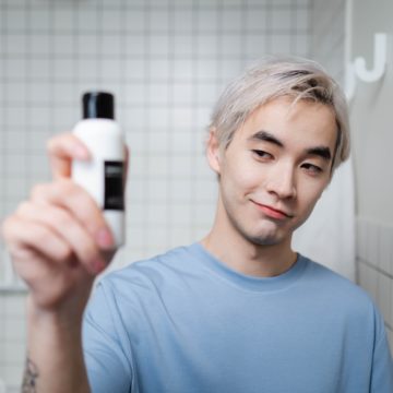 Junger Mann in Bad mit Duschgel in der Hand